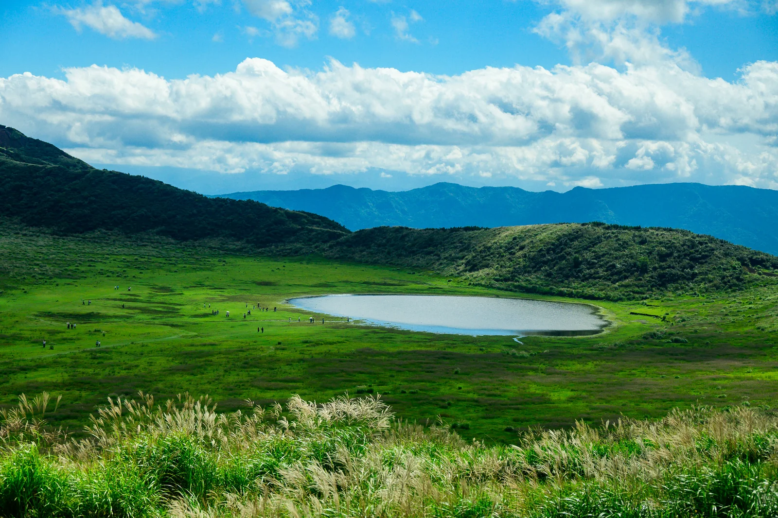 阿蘇盆地圓形火山湖與綠色草原，山景遠寬